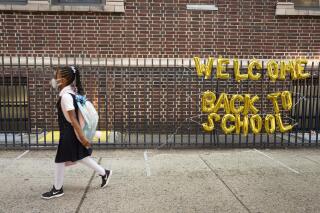 FILE - In this Sept. 13, 2021, file photo, a girl passes a "Welcome Back to School" sign as she arrives for the first day of class at Brooklyn's PS 245 elementary school in New York. COVID-19 deaths and cases in the U.S. have climbed back to where they were over the winter, fueled by children now back in their classrooms, loose mask restrictions and low vaccination levels. (AP Photo/Mark Lennihan, File)