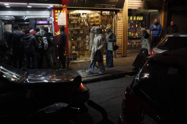 People walk past shops on a street in the Bab Touma neighborhood of the Old City of Damascus, Syria, Saturday, Dec. 14, 2024. (AP Photo/Leo Correa)