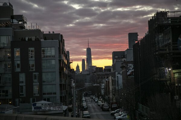 A man crosses a street against the backdrop of One World Trade Center at dusk in New York, on Saturday, March 21, 2020. Amid the coronavirus outbreak, the city, a place of familiar landmarks and well-trodden streets, has been thrown off kilter by an invisible adversary that is taking some of its people away and terrifying the rest. (AP Photo/Wong Maye-E)