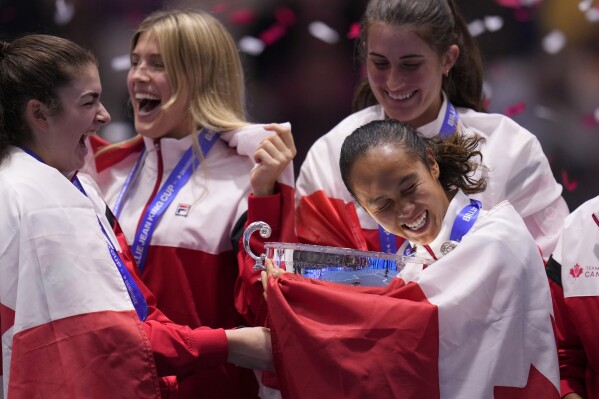 Canada's Leylah Fernandez, right, holds the trophy with member of her team after wining the final singles tennis match against Italy's Jasmine Paolini, during the Billie Jean King Cup finals in La Cartuja stadium in Seville, southern Spain, Spain, Sunday, Nov. 12, 2023. (AP Photo/Manu Fernandez)