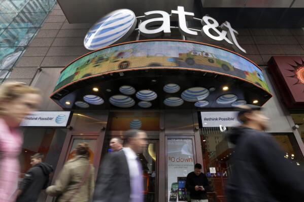 FILE - In this Oct. 21, 2014 file photo, people pass an AT&T store in New York's Times Square. Shares of the new Warner Bros. Discovery media giant, the $43 billion combination of Discovery and the AT&T spinoff WarnerMedia, have begun trading Monday, April 11, 2022. (AP Photo/Richard Drew, File)