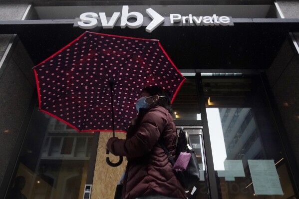 FILE - A pedestrian carries an umbrella past a Silicon Valley Bank Private branch in San Francisco, on March 14, 2023. In 2023, the financial industry faced a banking crisis of a scale not seen since 2008. Three midsized banks failed: Silicon Valley Bank, Signature Bank and First Republic Bank. (AP Photo/Jeff Chiu, File)