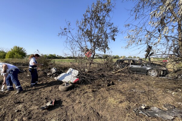 This photo released by the Hungarian Police, shows police investigators examining a plane crash site in the Borgond area, Hungary, Sunday, Sept. 10, 2023. Police say a small propeller-driven plane has crashed during an airshow in central Hungary killing two people and seriously injuring three people on the ground at the Borgond air show in Fejer county. (Hungarian Police via AP)