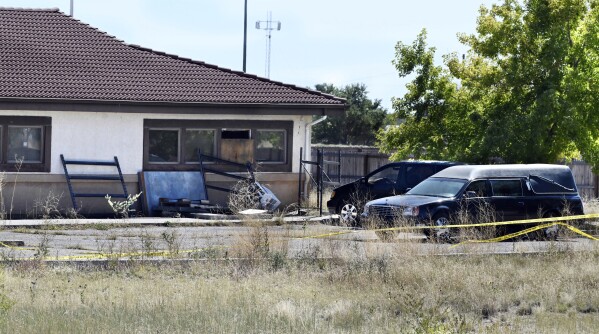 FILE - A hearse and debris can be seen at the rear of the Return to Nature Funeral Home, Oct. 5, 2023, in Penrose, Colo. The couple who owned the Colorado funeral home — where 190 decaying bodies were discovered last year — have been indicted on federal charges for fraudulently obtaining nearly $900,000 in pandemic relief funds from the U.S. government, according to court documents unsealed Monday, April 15, 2024. (Jerilee Bennett/The Gazette via AP, File)