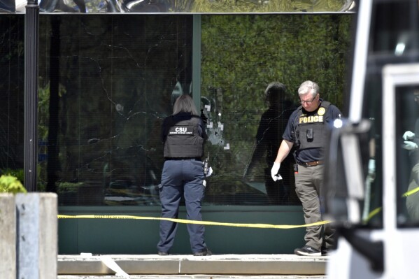 FILE - A Louisville Metro Police crime scene technician photographs bullet holes in the glass of the Old National Bank building in Louisville, Ky., Monday, April 10, 2023. The man who shot and killed five coworkers at a Louisville bank in April appears to have done little advanced planning and didn’t have extensive knowledge of how to operate the gun he used in the shooting, according to an investigative file released Tuesday, Nov. 21, 2023, by police. (AP Photo/Timothy D. Easley, File)