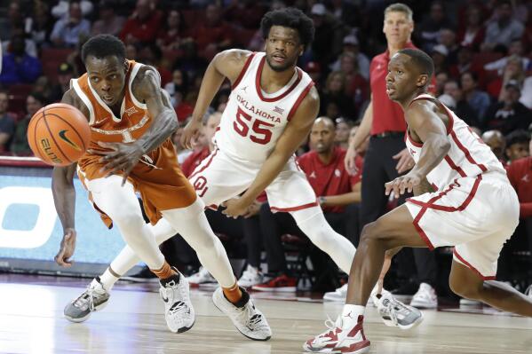 Texas guard Andrew Jones (1) races after a loose ball as Oklahoma guard Elijah Harkless (55) watches during the first half of an NCAA college basketball game Tuesday, Feb. 15, 2022, in Norman, Okla. (AP Photo/Alonzo Adams)