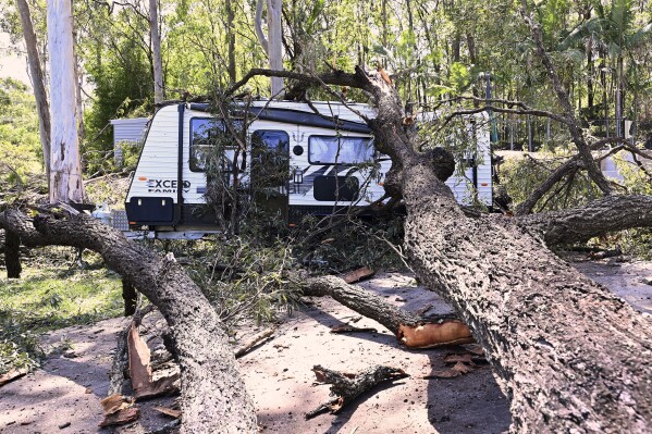 A fallen tree lays across a camping trailer near the Gold Coast, Australia Tuesday, Dec. 26, 2023. At least nine people have died in wild weather in the Australian eastern states of Queensland and Victoria, officials said on Wednesday. (Dave Hunt/AAP Image via AP)
