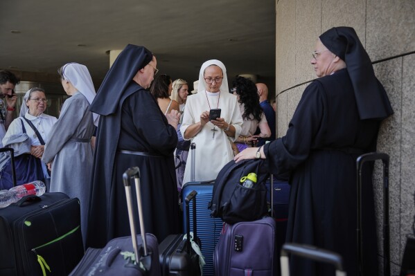 Citizens of Poland and Austria assemble at a hotel in Tel Aviv, Israel, for evacuation amid heavy strikes on Israel by Iran on Tuesday, June 17, 2025. (AP Photo/Baz Ratner)