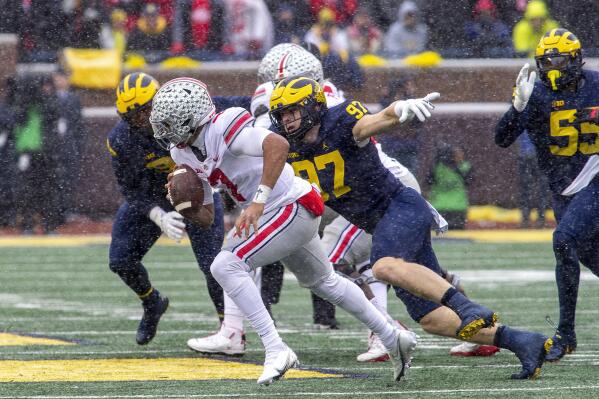 Ohio State quarterback C.J. Stroud (7) scrambles away from Michigan defensive end Aidan Hutchinson (97) in the second quarter of an NCAA college football game in Ann Arbor, Mich., Saturday, Nov. 27, 2021. Michigan coach Jim Harbaugh said star defensive end Aidan Hutchinson should be strongly considered for the Heisman Trophy after he had three sacks, setting a single-season record for college football team, in a win over Ohio State that put the Wolverines in the Big Ten championship game and national title race. (AP Photo/Tony Ding)