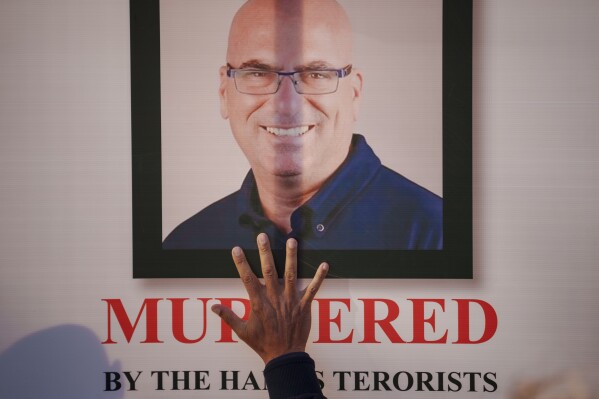 FILE - A man man touches a photograph of a victim during a rally in solidarity with Israel and those held hostage by Hamas in Gaza in Bucharest, Romania on Nov. 12, 2023. (AP Photo/Andreea Alexandru, File)