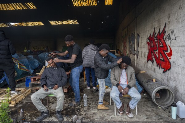 Migrants get their hair cut at an abandoned warehouse turned migrant camp in Calais, northern France, on Wednesday, May 15, 2024. (AP Photo/Bernat Armangue)