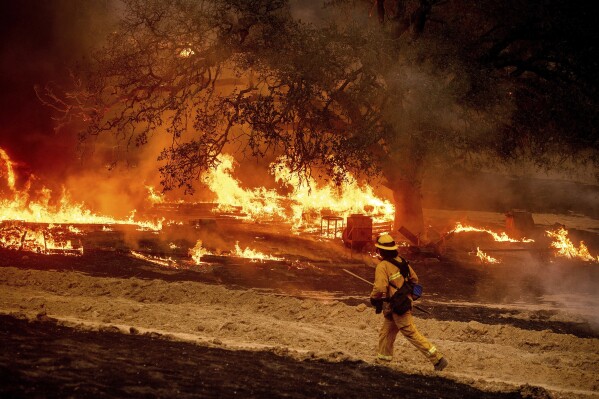 A firefighter passes flames while battling the Glass Fire in a Calistoga, Calif., vineyard Oct. 1, 2020. (AP Photo/Noah Berger, File)
