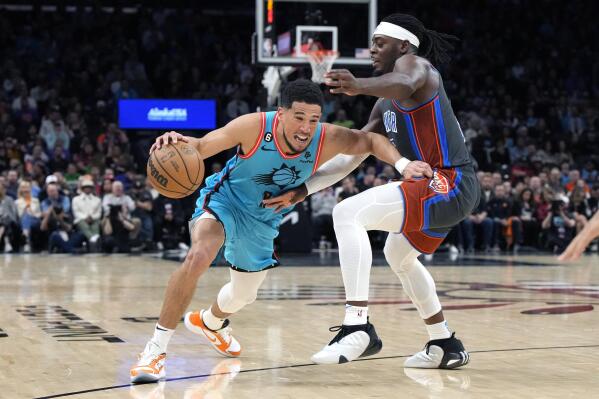 Phoenix Suns guard Devin Booker (1) drives on Oklahoma City Thunder guard Luguentz Dort during the second half of an NBA basketball game Friday, Feb. 24, 2023, in Phoenix. The Suns won 124-115. (AP Photo/Rick Scuteri)