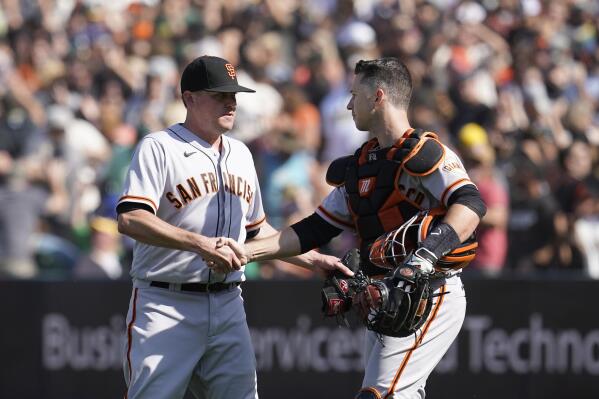 San Francisco Giants pitcher Jake McGee, left, celebrates with catcher Buster Posey after they defeated the Oakland Athletics in a baseball game in Oakland, Calif., Sunday, Aug. 22, 2021. (AP Photo/Jeff Chiu)