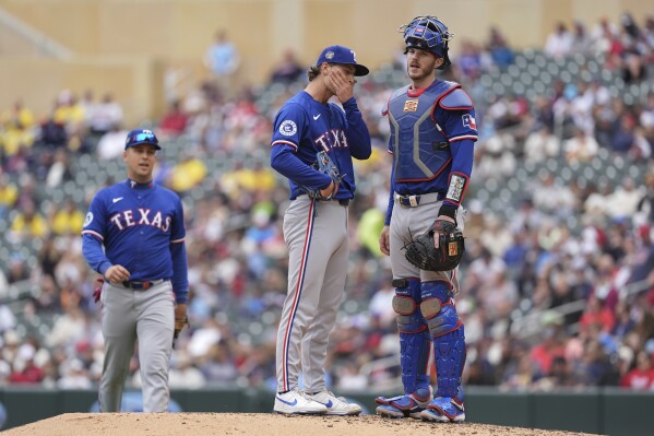 Texas Rangers reliever Jacob Latz, center, waits as manager Bruce Bochy (not shown) comes to make a pitching change during the seventh inning of a baseball game against the Minnesota Twins, Sunday, May 26, 2024, in Minneapolis. (AP Photo/Abbie Parr)