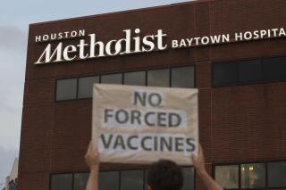 FILE - In this June 7, 2021, file photo, a person holds a sign to protest at Houston Methodist Hospital in Baytown, Texas, a policy that says hospital employees must get vaccinated against COVID-19 or lose their jobs. Over 150 employees at Houston Methodist system, who refused to get a COVID-19 vaccine, have been fired or resigned after a judge dismissed an employee lawsuit over the vaccine requirement, said Houston Methodist system spokesperson Gale Smith on Tuesday, June 22, 2021. (Yi-Chin Lee/Houston Chronicle via AP, File)