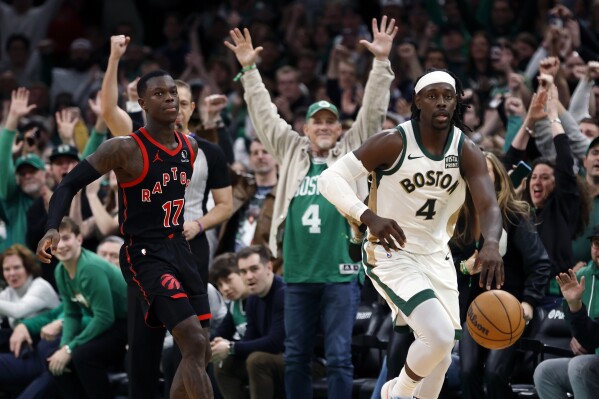 Fans react behind Boston Celtics' Jrue Holiday (4) and Toronto Raptors' Dennis Schroder (17) after the Celtics prevented the Raptors from scoring in the final seconds of the fourth quarter during an NBA basketball game, Friday, Dec. 29, 2023, in Boston. (AP Photo/Michael Dwyer)