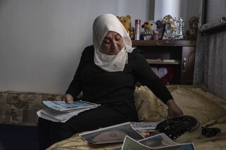 Hamrin Alouji, the mother of 13-year-old Peyal Aqil, goes through her daughter's photographs at their family home in Qamishli, Syria, on Monday, June 5, 2023. Alouji said her daughter was coming home with her friends on May 21 after a school exam when a recruiter for the Revolutionary Youth approached her - the youth branch of the Democratic Union Party (PYD), and entered a center belonging to the group with him. Her friends waited for her outside, but she never came out. (AP Photo/Baderkhan Ahmad)