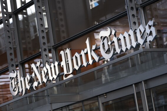 A sign for The New York Times hangs above the entrance to its building, May 6, 2021, in New York. (AP Photo/Mark Lennihan, File)