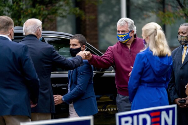 Democratic presidential candidate former Vice President Joe Biden fist bumps a supporter as he leaves after visiting people outside a voter service center, Monday, Oct. 26, 2020, in Chester, Pa. (AP Photo/Andrew Harnik)