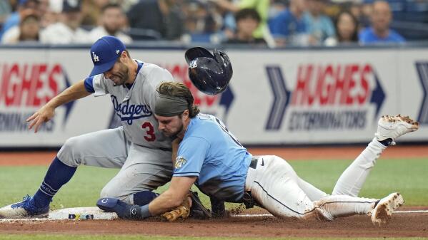 Tampa Bay Rays' Josh Lowe loses his helmet as he steals third base ahead of the tag by Los Angeles Dodgers' Chris Taylor (3) during the fourth inning of a baseball game Sunday, May 28, 2023, in St. Petersburg, Fla. (AP Photo/Chris O'Meara)