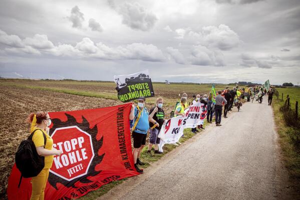 Environmental and climate activists as well as residents of neighbouring villages have form a human chain on the edge of the Garzweiler open-cast mine in Juechen, Germany, Saturday, Aug. 7, 2021. About 2,500 people have protested for a quick exit from coal mining in western Germany. They formed a four-kilometer (2.5-mile) human chain between the villages of Luetzerath and Keyenberg on Saturday. Protesters were campaigning to save Luetzerath from being bulldozed to make way for a coal mine. (Malte Krudewig/dpa via AP)