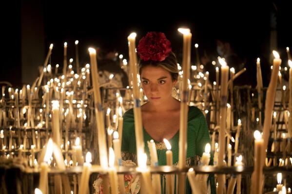 A pilgrim lights a candle in the sanctuary of the virgin of the Rocío in the village of El Rocío in Almonte, Spain, on Saturday June 4, 2022, during the annual pilgrimage in which hundreds of thousands of devotees of the Virgin del Rocio converge in and around the shrine. After a two-year hiatus forced by the pandemic, tens of thousands of pilgrims descended on the tiny Spanish village of El Rocío to take part in riotously colorful and ancient festival, la Romería del Rocío, or the Rocío virgin pilgrimage. (AP Photo/Joan Mateu Parra)