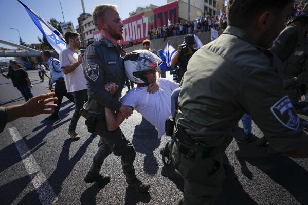 Israeli border police officers disperse demonstrators blocking a highway during a protest against plans by Prime Minister Benjamin Netanyahu's government to overhaul the judicial system, in Tel Aviv, Israel, Thursday, March 9, 2023. (AP Photo/Ariel Schalit)