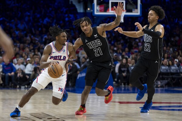 Philadelphia 76ers' Tyrese Maxey, left, drives to the basket against Brooklyn Nets' Noah Clowney, center, and Jalen Wilson, right, during the second half of an NBA basketball game, Sunday, April 14, 2024, in Philadelphia. The 76ers won 107-86. (AP Photo/Chris Szagola)