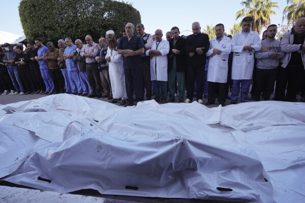 Palestinians pray for their relatives killed in the Israeli bombardment of the Gaza Strip in front of the morgue of al Aqsa Hospital in Deir al Balah, Gaza Strip, Tuesday, Nov. 21, 2023. (AP Photo/Adel Hana)