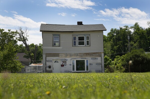 An abandoned home sits across from a vacant lot Wednesday, May 22, 2024, in Hannibal, Mo. Devastating flooding, driven in part by climate change, is taking an especially damaging toll on communities that once thrived along the banks of the Mississippi River. (AP Photo/Jeff Roberson)