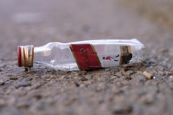An empty miniature bottle that once contained liquor rests on a street near a sidewalk, Monday, April 3, 2023, in Boston. A Boston city councilor has proposed barring city liquor stores from selling the single-serve bottles that hold 100 milliliters or less of booze both as a way to address alcohol abuse and excessive litter. (AP Photo/Steven Senne)