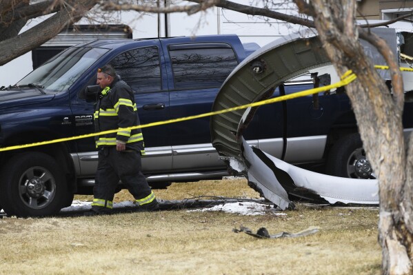 FILE - A North Metro firefighter walks past a large piece of a United airplane engine in the front yard of a home on Elmwood Street near E. 13th Avenue, Saturday, Feb. 20, 2021, in Broomfield, Colo. An engine on a United Airlines jet broke up over Denver in 2021 because of wear and tear on a fan blade that was not adequately inspected for signs of cracking, federal investigators said Friday, Sept. 8, 2023. (Andy Cross/The Denver Post via AP, File)