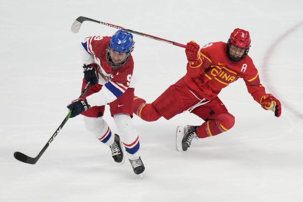 Czech Republic's Alena Mills (9) passes the puck away from China's Qiqi Lin (8) during a preliminary round women's hockey game at the 2022 Winter Olympics, Thursday, Feb. 3, 2022, in Beijing. (AP Photo/Petr David Josek)
