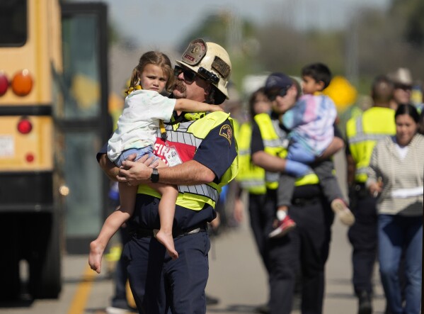 Children are transported from a fatal school bus crash on Texas State Highway 21 near Caldwell Road on Friday, March 22, 2024, in Bastrop, Texas. Texas authorities say a school bus with more than 40 pre-K students collided with a concrete truck and rolled over while returning from a field trip, killing a boy on the bus and a man in another vehicle. (Jay Janner/Austin American-Statesman via AP)