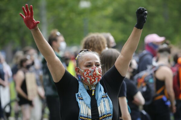 FILE - In this June 13, 2020, file photo, Roberta Huss, who identified herself as a proud Dakota Sioux woman, raises her fist as she joins others during a demonstration  in Salt Lake City, against police brutality and discrimination against people of color following the death of George Floyd. The racial reckoning in the United States spurred by the death of Floyd has reinvigorated Native Americans, Asian Americans, Latinos and other people of color to fight back against the racism and discrimination they also have experienced for decades. But the Black Lives Matter movement has also forced minority communities to come to terms with their own internal biases and the conflicts among them. (AP Photo/Rick Bowmer, File)