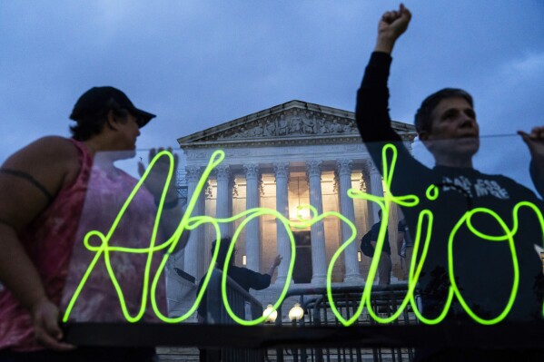 FILE - Activists mark the first anniversary of the Supreme Court's decision in Dobbs v. Jackson Women's Health Organization, by displaying neon signage in support of abortion access in front of the Supreme Court on June 23, 2023, in Washington. A report finds the total number of monthly abortions in the U.S. increased after state bans started kicking in in 2022. (AP Photo/Nathan Howard, File)