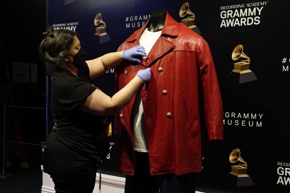 Collections assistant Cyrene Cruz primps a red leather jacket that was worn by the late rapper The Notorious B.I.G. in preparation for the exhibit "Hip-Hop America: The Mixtape," at the Grammy Museum, Friday, Sept. 1, 2023, in Los Angeles. The Grammy Museum announced on Wednesday that it is launching the exhibit, celebrating 50 years of the genre. It will open on October 7 and run until September 4, 2024. (AP Photo/Chris Pizzello)