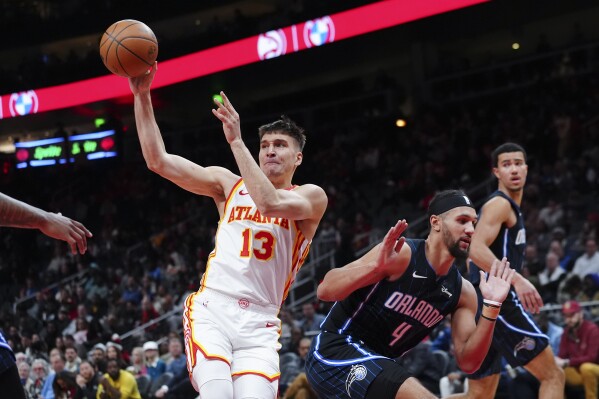 Atlanta Hawks guard Bogdan Bogdanovic (13) passes as he drives against Orlando Magic guard Jalen Suggs (4) during the first half of an NBA basketball game Wednesday, Jan. 17, 2024, in Atlanta. (AP Photo/John Bazemore)