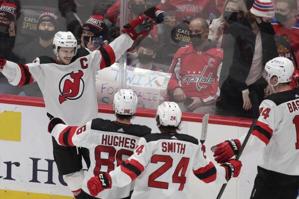 New Jersey Devils' Nico Hischier, top left, celebrates with his teammates, from left to right, Jack Hughes, Ty Smith (24) and Nathan Bastian (14) after scoring the winning goal in overtime of an NHL hockey game against the Washington Capitals, Sunday, Jan. 2, 2022, in Washington. (AP Photo/Luis M. Alvarez)