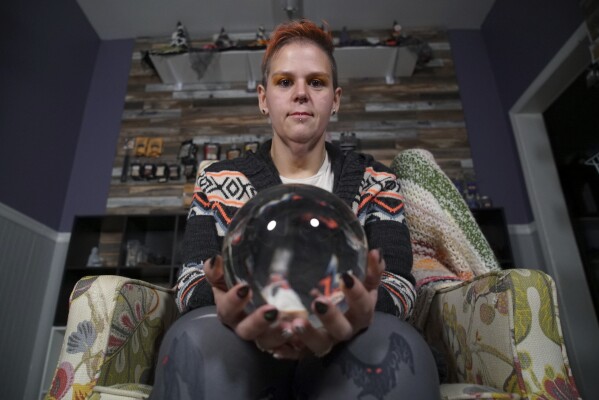 Melissa Sell poses for a portrait with a crystal ball in her shop, Every Witch Way, on the main street of Mount Holly Springs, Pa., on Monday, Oct. 30, 2023. “If it’s a big news story on the TV, the majority of the time it’s to distract us from something else. Every time you turn around there’s another news story with another agenda distracting all of us,” she says. (AP Photo/Allen G. Breed)
