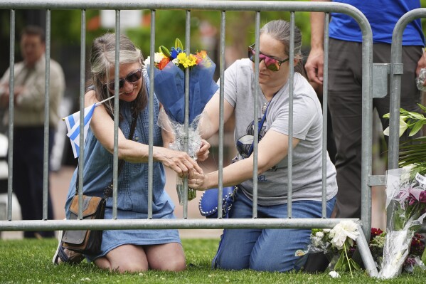 From left, Lisa Turnquist and Carrie Spyva-McIlvaine place a bouquet of flowers at a growing memorial outside of the Boulder County, Colo., courthouse after Sunday's attack Monday, June 2, 2025, in Boulder, Colo. (AP Photo/David Zalubowski)