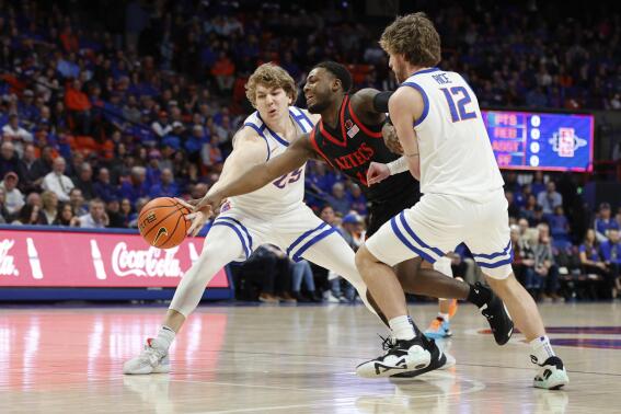 San Diego State's Darrion Trammell moves the ball between Boise State's Lukas Milner and Max Rice (12) during the first half of an NCAA college basketball game in Boise, Idaho, Tuesday, Feb. 28, 2023. (AP Photo/Otto Kitsinger)