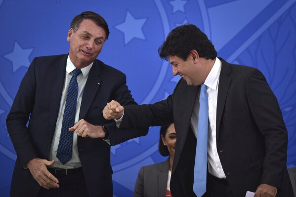 Brazil's President Jair Bolsonaro, left, greets his outgoing Health Minister Luiz Henrique Mandetta during the swearing-in ceremony for the new Health Minister Nelson Teich, not in picture, at Planalto palace in Brasilia, Brazil, Friday, April 17, 2020. Mandetta had garnered support for his handling of the pandemic that included promotion of broad isolation measures enacted by state governors, but had drawn the ire of Bolsonaro, who has said shutting down the economy would cause more damage than confining only high-risk Brazilians. (AP Photo/Andre Borges)