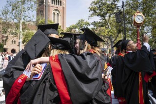 File - Graduates embrace during Southern California's 140th commencement ceremony, on May 12, 2023, in Los Angeles. Interest on federal student loans has started accumulating again after a three-year pause because of the COVID-19 pandemic. Borrowers still have another month before they'll need to start paying back loans. (Sarah Reingewirtz/The Orange County Register via AP, File)