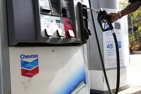 A customer replaces the pump dispenser at a Chevron gas station in Columbus, Miss., Monday, Oct. 23, 2023. Chevron is buying Hess Corp. for $53 billion as major producers seize the initiative while oil prices surge. (AP Photo/Rogelio V. Solis)