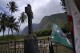 Flags blow in the breeze at the grave of Father Damien outside St. Philomena Church on Kalaupapa, Hawaii, on Tuesday, July 18, 2023. Damien was canonized a Catholic saint in 2009 for his work taking care of the physical and spiritual needs of leprosy patients in the 1800s. His body was moved to his home country of Belgium in 1936. Only the priest's hand remains, which was reburied at the site in 1995. (AP Photo/Jessie Wardarski)