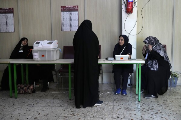 Staff members of a polling station attend to their stations during the parliamentary runoff elections in Tehran, Iran, Friday, May 10, 2024. Iranians voted Friday in a runoff election for the remaining seats in the country's parliament after hard-line politicians dominated March balloting. (Ǻ Photo/Vahid Salemi)