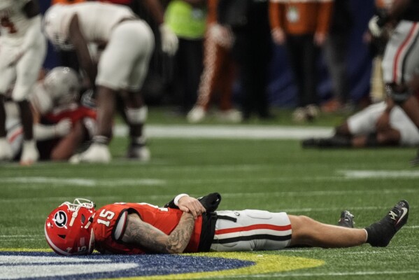 Georgia quarterback Carson Beck (15) lies on the turf injured against Texas during the first half of the Southeastern Conference championship NCAA college football game, Saturday, Dec. 7, 2024, in Atlanta. (AP Photo/John Bazemore)