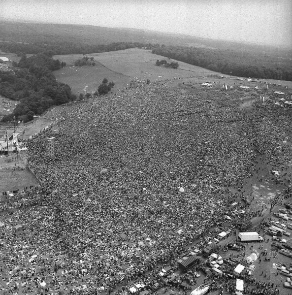 FILE - This Aug. 16, 1969 file photo shows a crowd of about 400,000 people attending the Woodstock Music and Arts Festival in Bethel, N.Y. Woodstock was staged 80 miles northwest of New York City on a bucolic hillside owned by dairy farmer Max Yasgur. It was great spot for peaceful vibes, but miserable for handling the hordes coming in by car. Fifty years later, memories of the rainy weekend Aug. 15-18, 1969, remain sharp among people who were in the crowd and on the stage. (AP Photo, File)